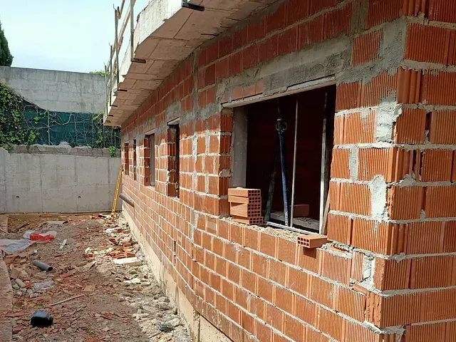 Se está construyendo un muro de ladrillos con muchas ventanas.