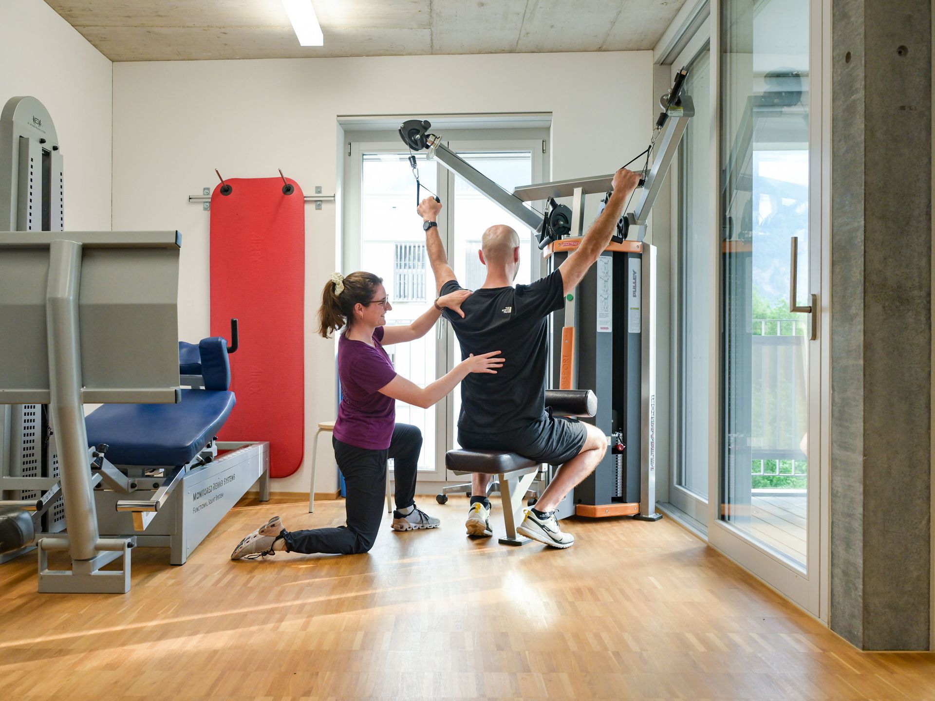 Eine Frau hilft einem Mann bei Übungen in einem Fitnessstudio