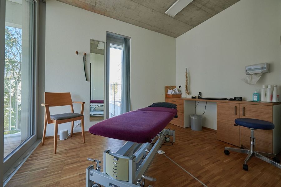 In einem Zimmer steht ein lila Sofa neben einem Stuhl.