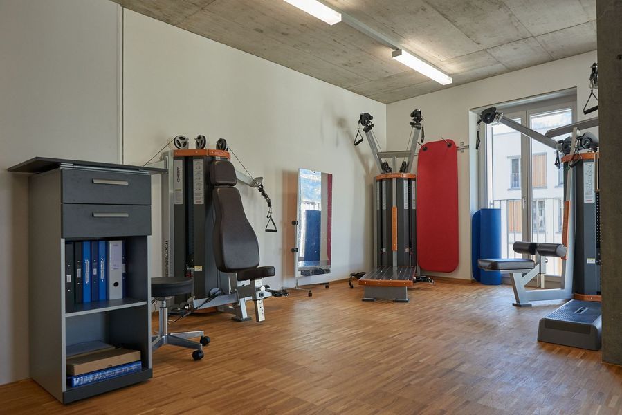 Ein Fitnessstudio mit Holzboden und vielen Trainingsgeräten.