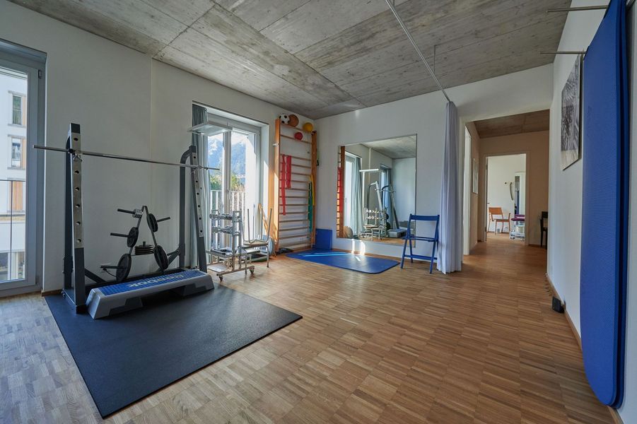 Ein großer Raum mit Holzboden und Fitnessgeräten.