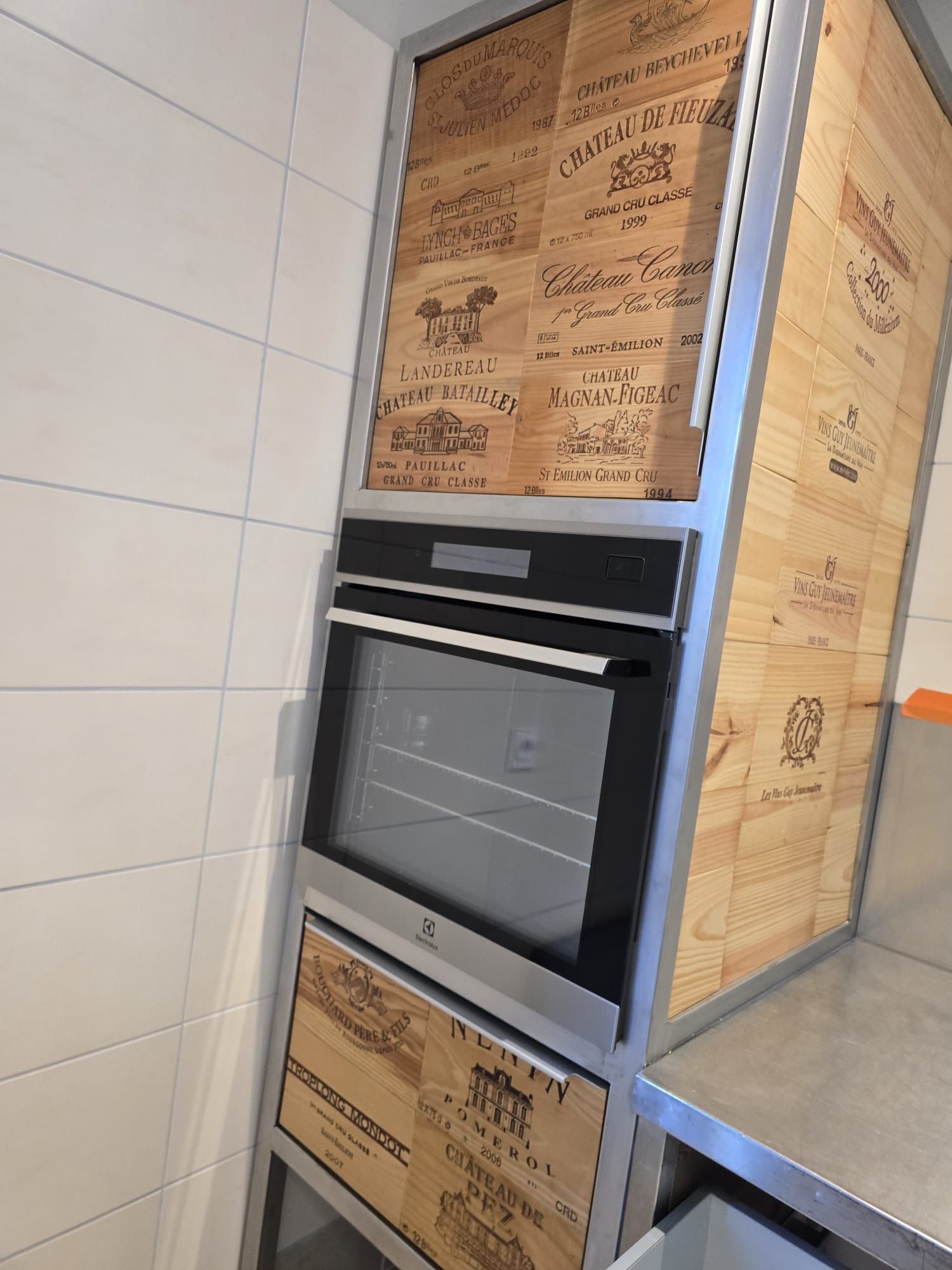 Four encastré, emballé dans du carton de protection, installé à côté d'un mur et d'un plan de travail carrelés.