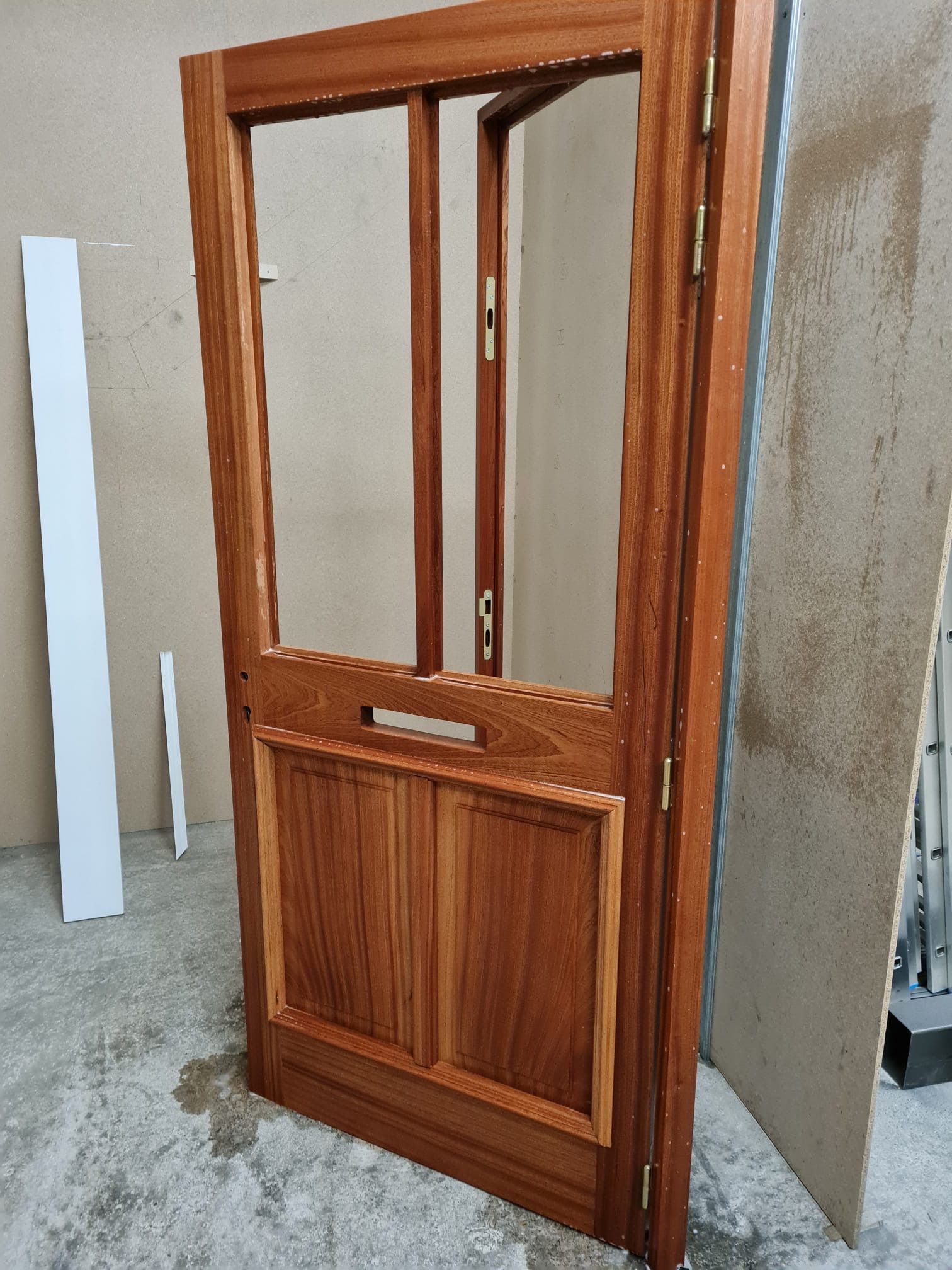 Porte vitrée à cadre en bois, placée à l'intérieur contre un mur en béton.