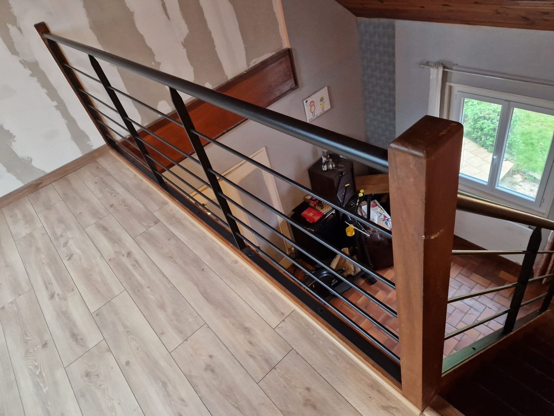 Escalier de mezzanine avec rampe en bois et parquet clair donnant sur un niveau inférieur.