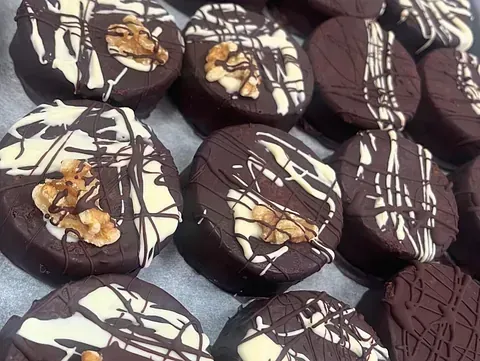 Un primer plano de una bandeja de galletas de chocolate con nueces encima.