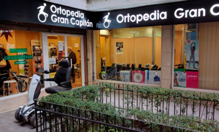 Un scooter está estacionado frente a una tienda llamada ortopedia gran capitan