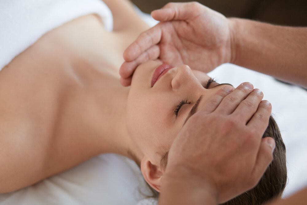 Una mujer está recibiendo un masaje facial en un spa.