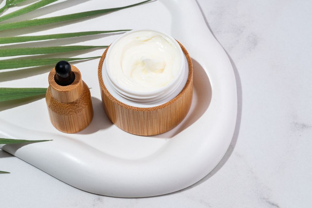 Un tarro de crema está sobre un plato blanco al lado de un gotero.