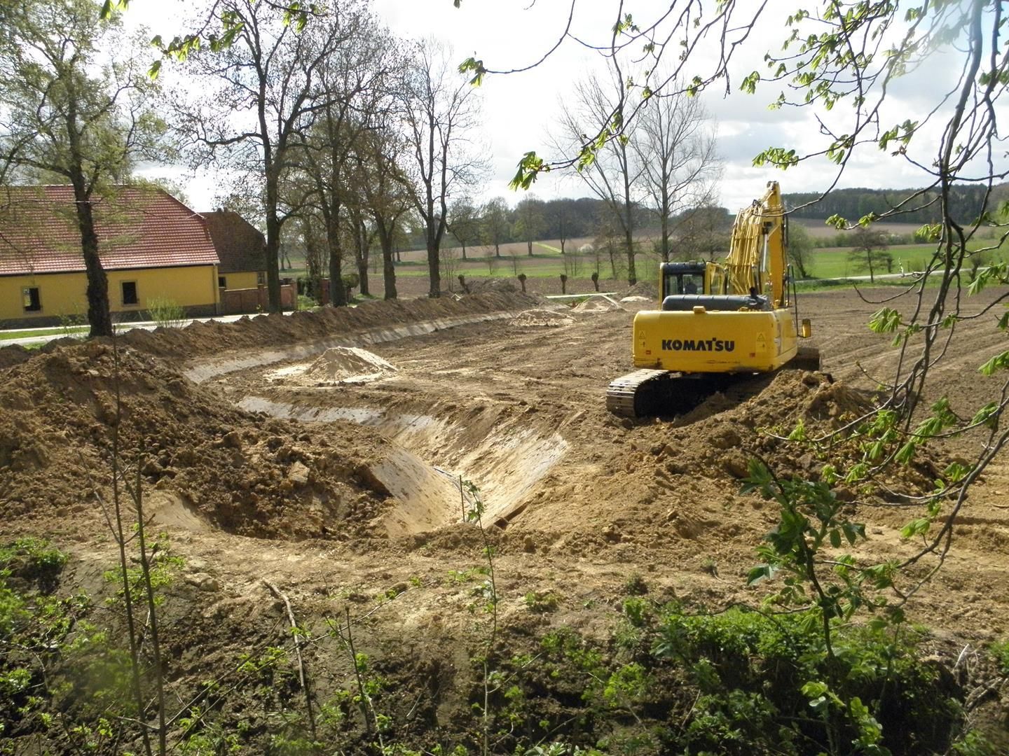Ein gelber Komatsu-Bagger gräbt ein Loch in den Dreck