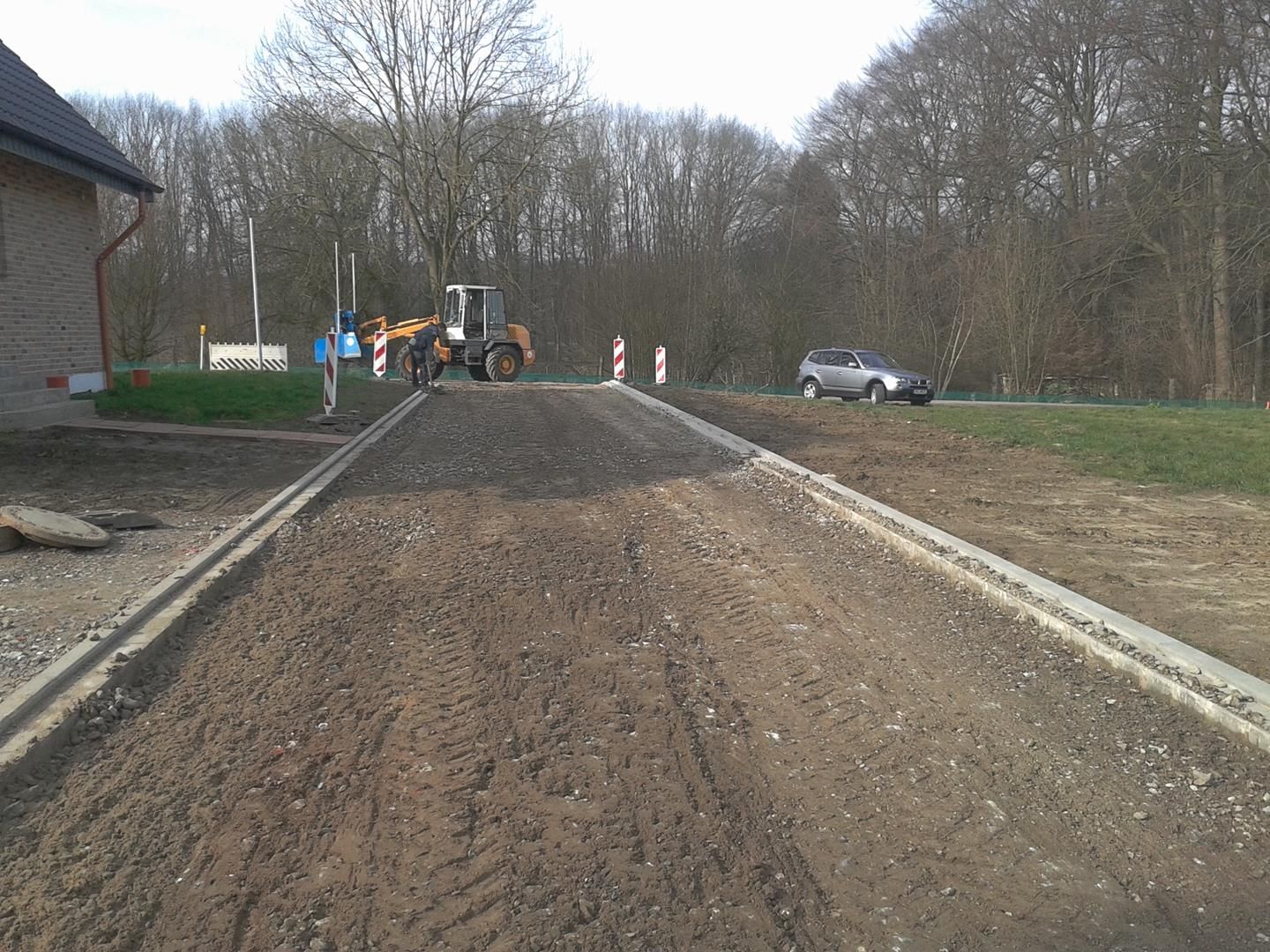 Ein Traktor fährt einen unbefestigten Weg neben einem Haus entlang