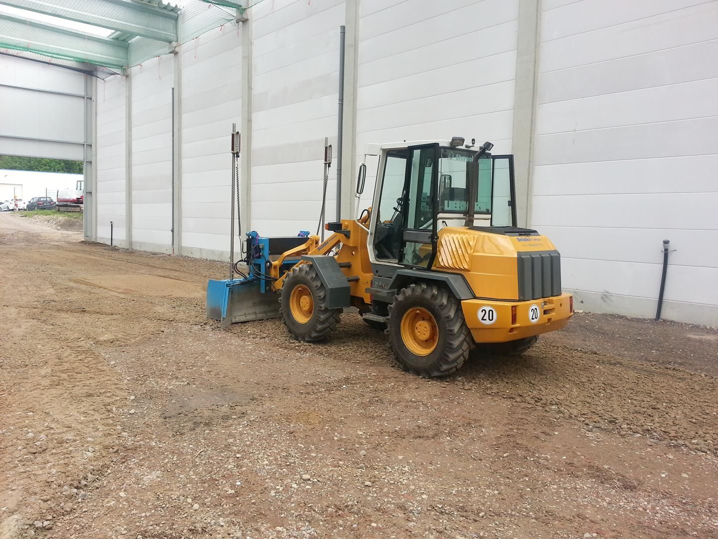 Vor einem Gebäude steht ein gelber Bulldozer