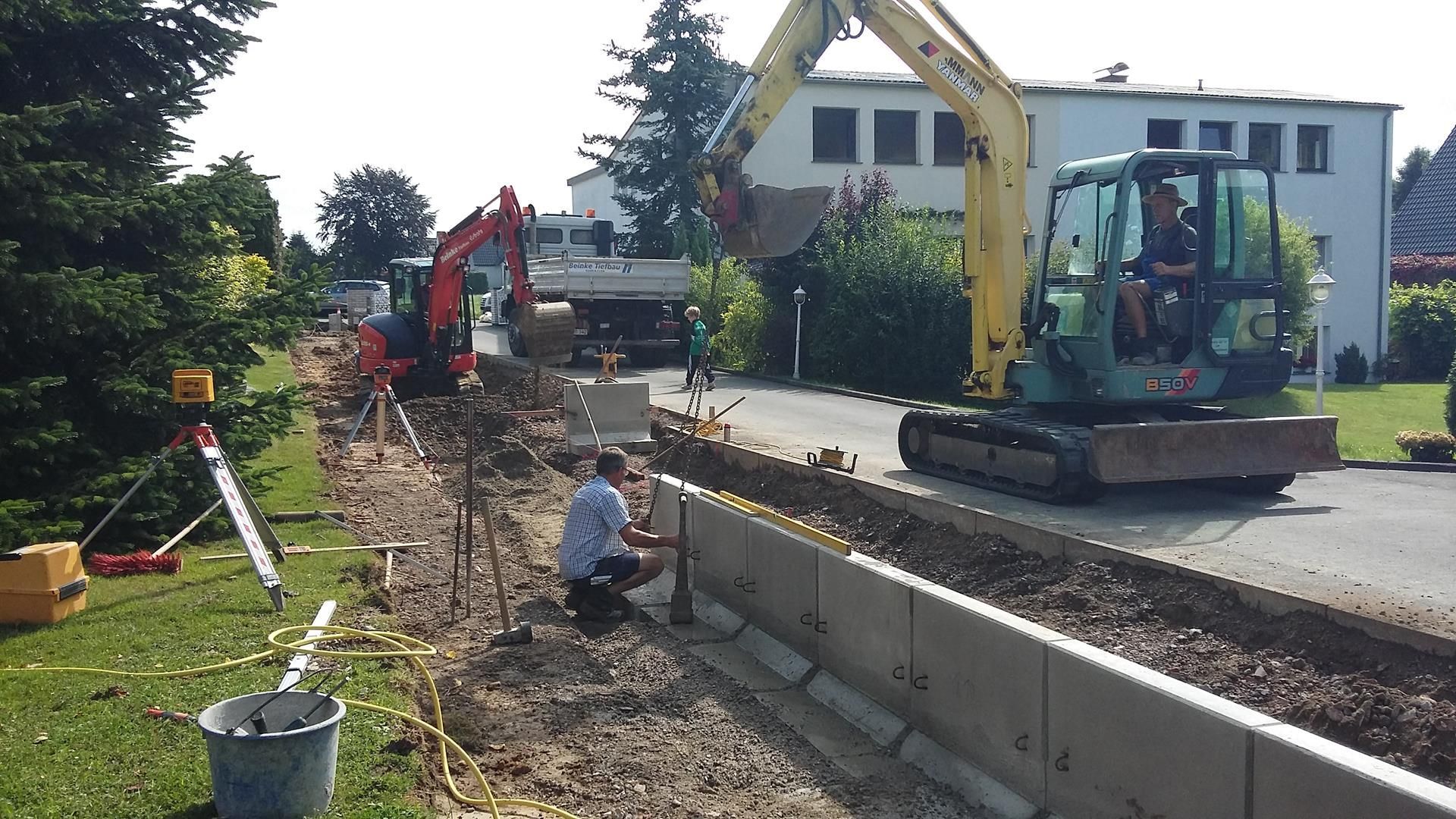 Ein Mann kniet vor einem Baufahrzeug
