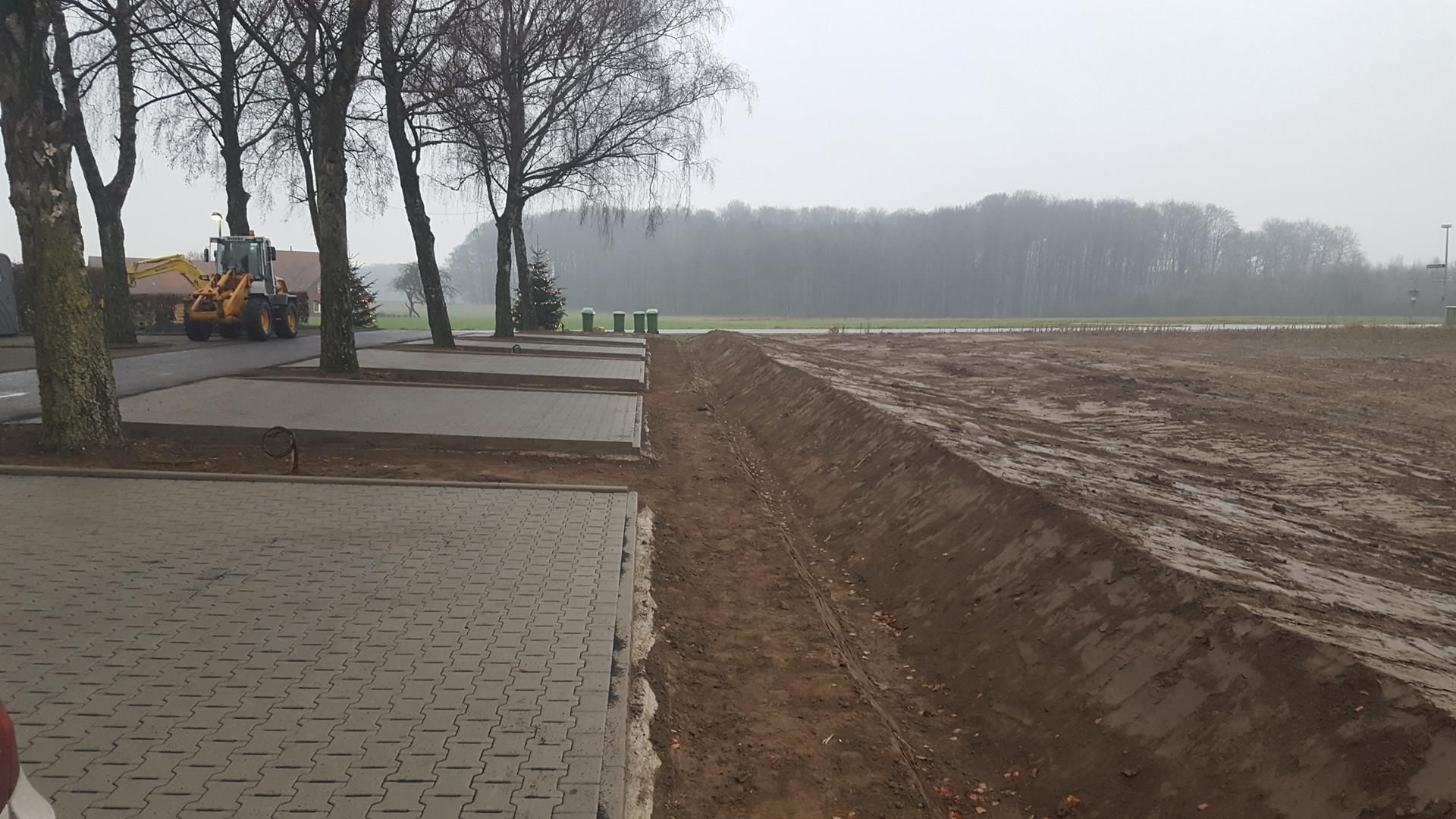 Ein Traktor fährt einen unbefestigten Weg entlang, der neben einer gepflasterten Straße verläuft.