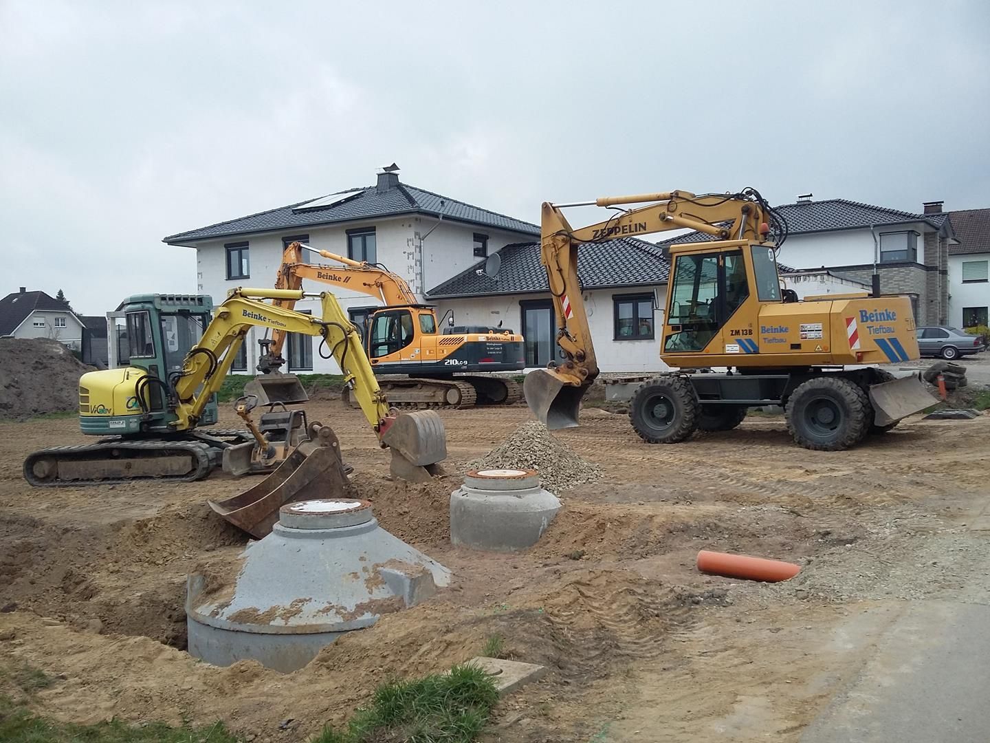 Vor einem Haus parken ein paar Baufahrzeuge