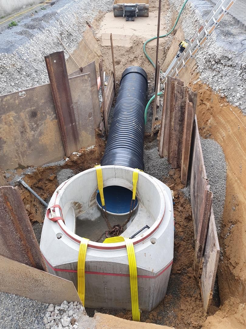 In einem Loch im Boden wird ein Rohr verlegt.