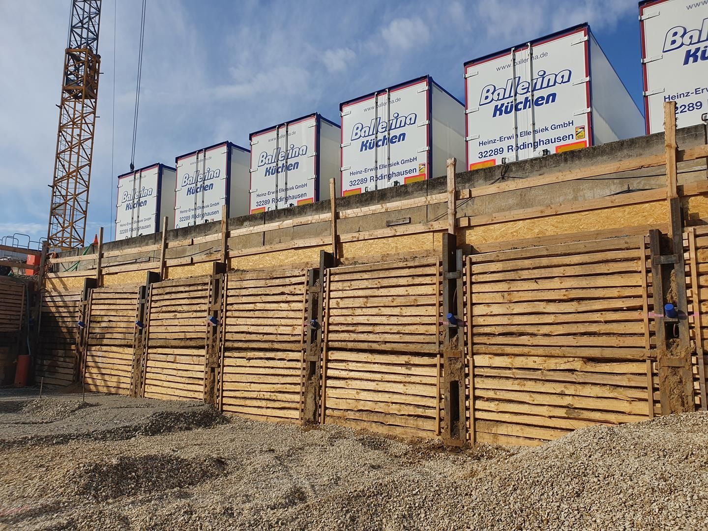 Auf einer Holzwand steht eine Reihe von Schiffscontainern.