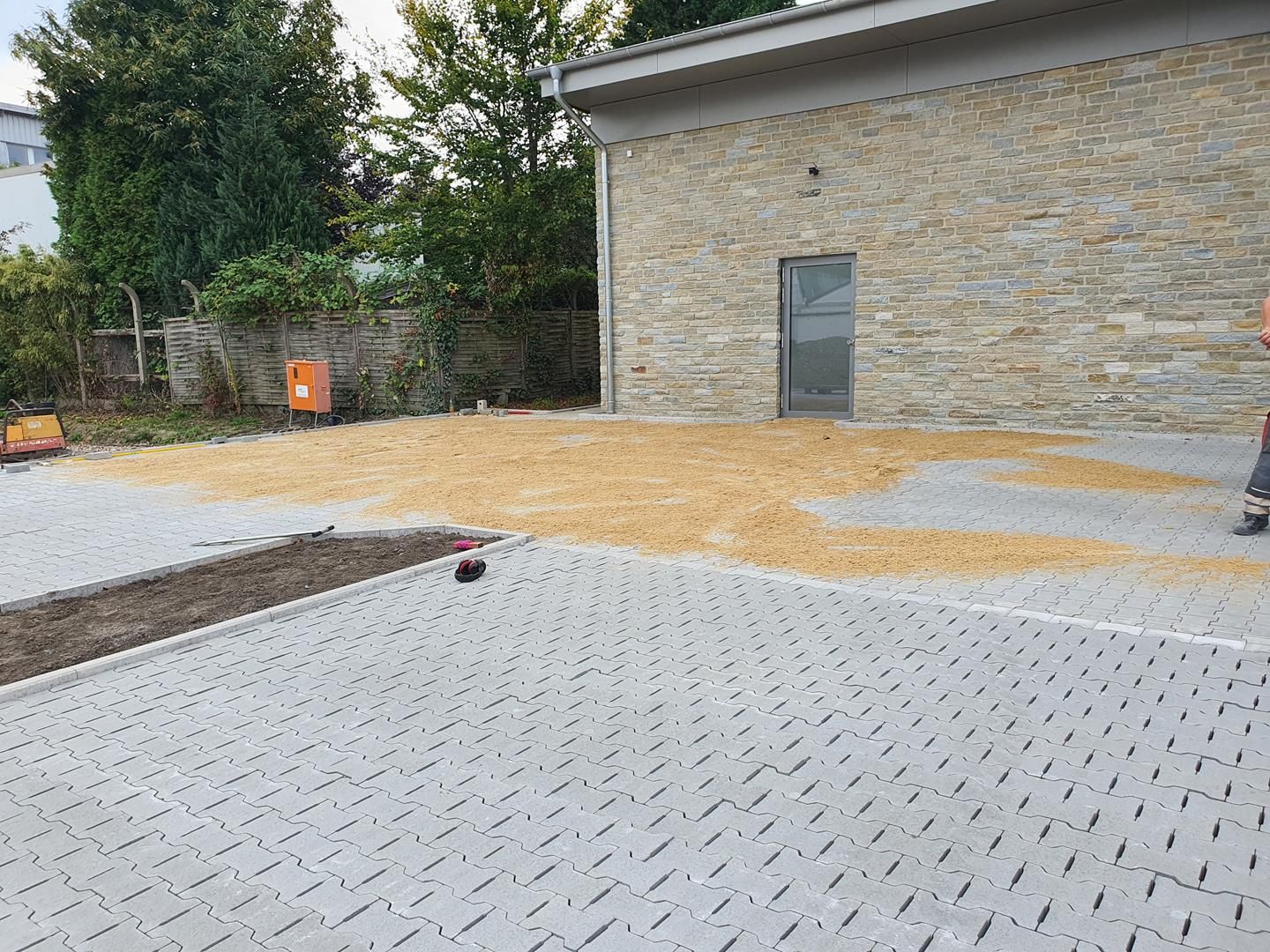 Ein Mann steht auf einer Backsteinauffahrt vor einem Steingebäude.