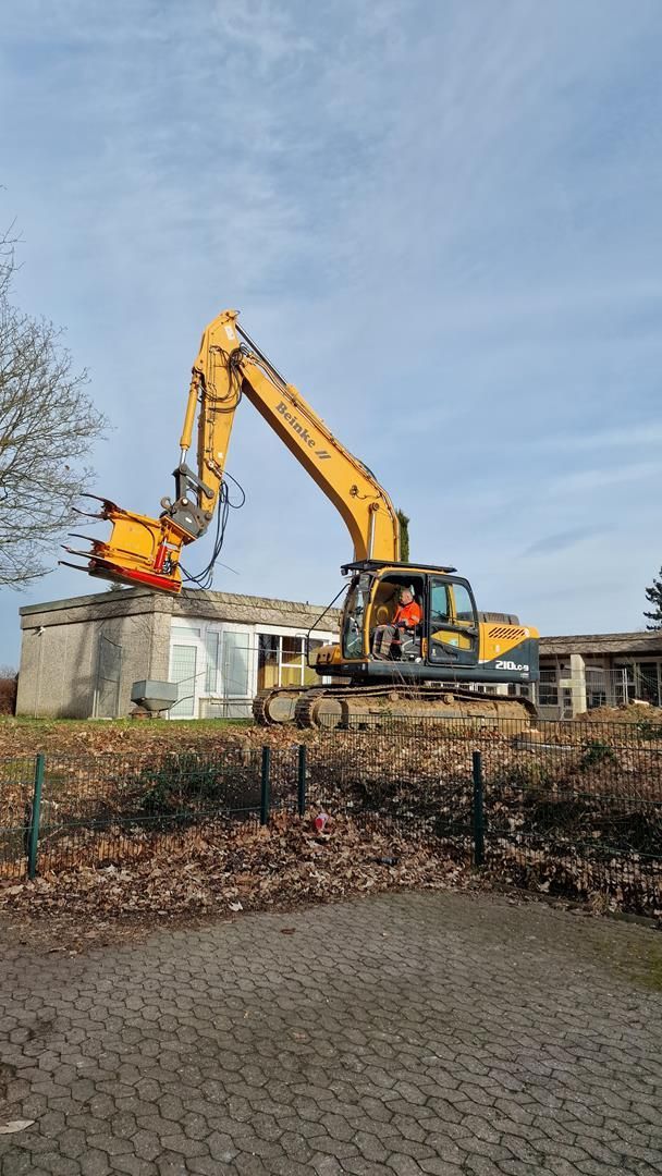 Ein großer gelber Bagger zerstört ein Gebäude.