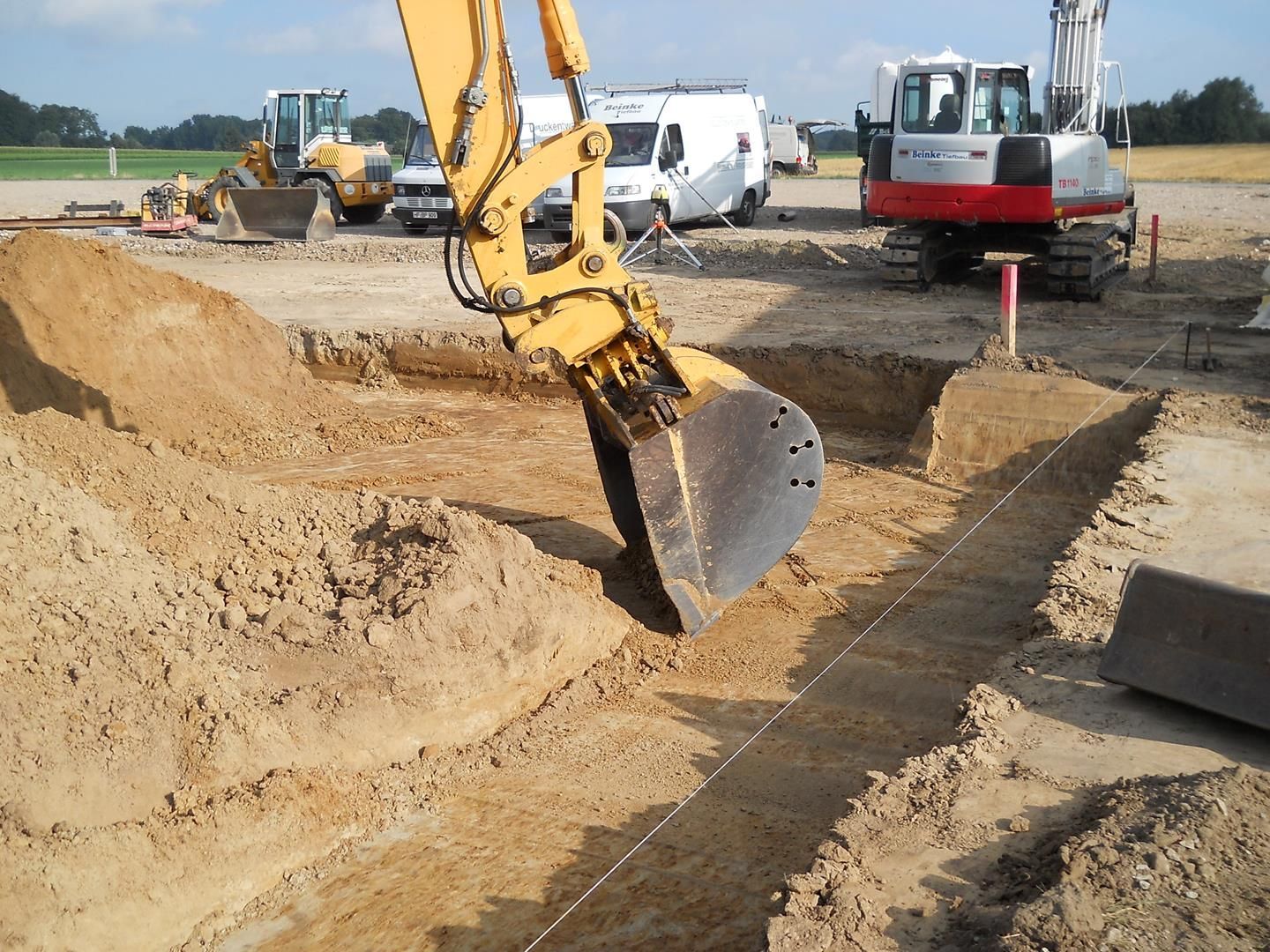 Ein gelber Bagger gräbt ein Loch in den Dreck