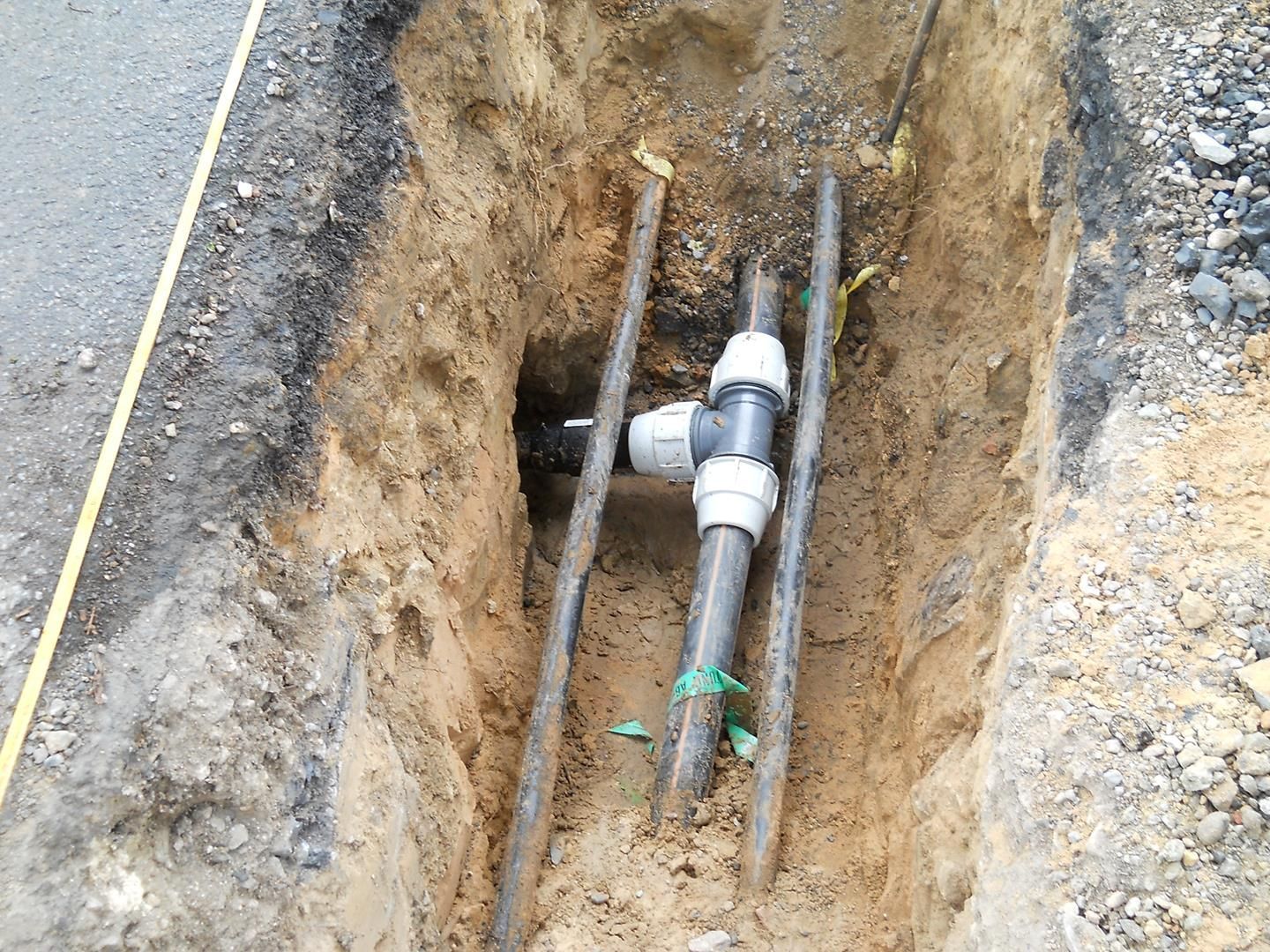 Ein paar Rohre liegen in der Erde in einem Loch.