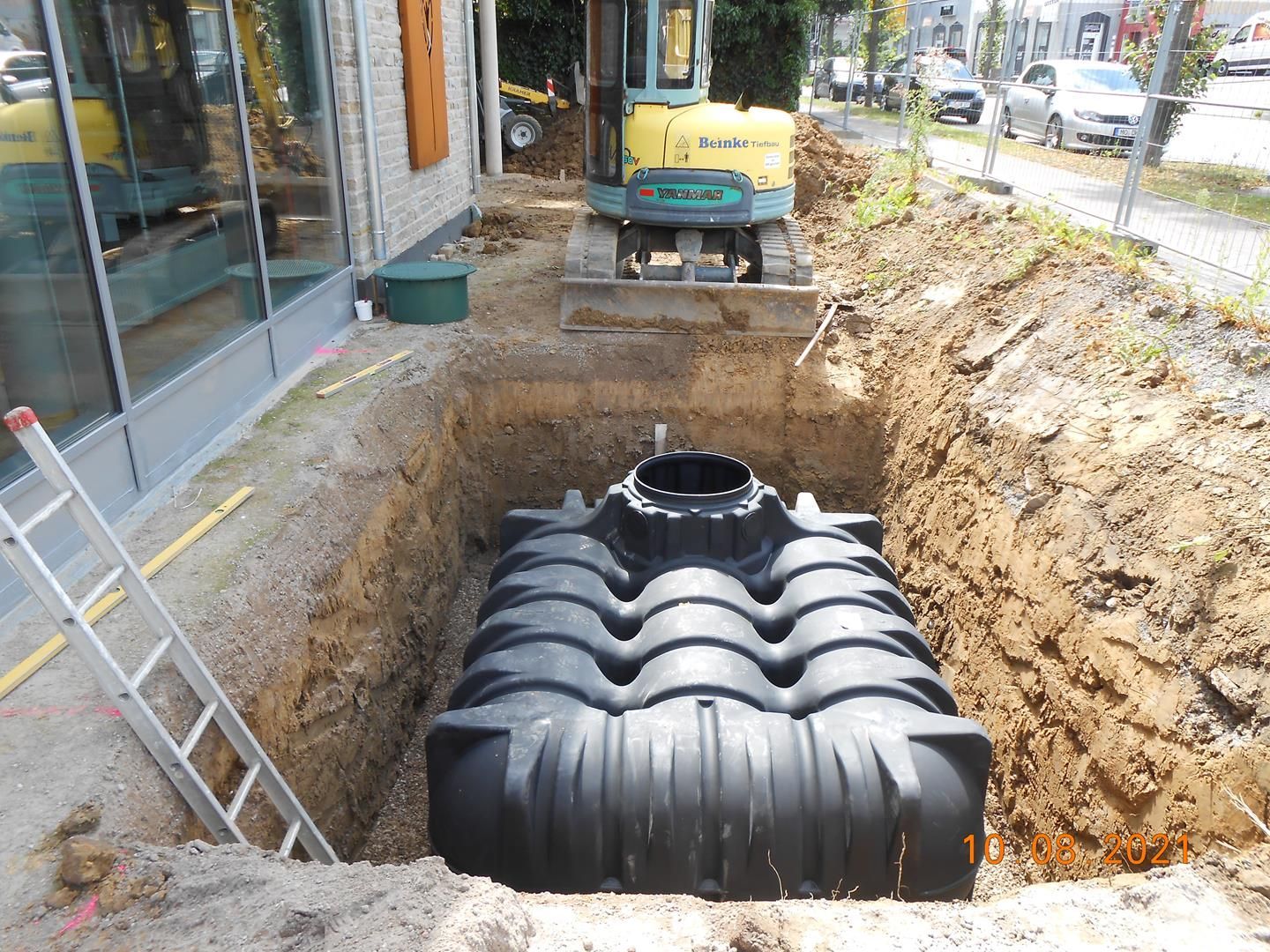 In einem Loch im Boden wird ein großer schwarzer Tank installiert.
