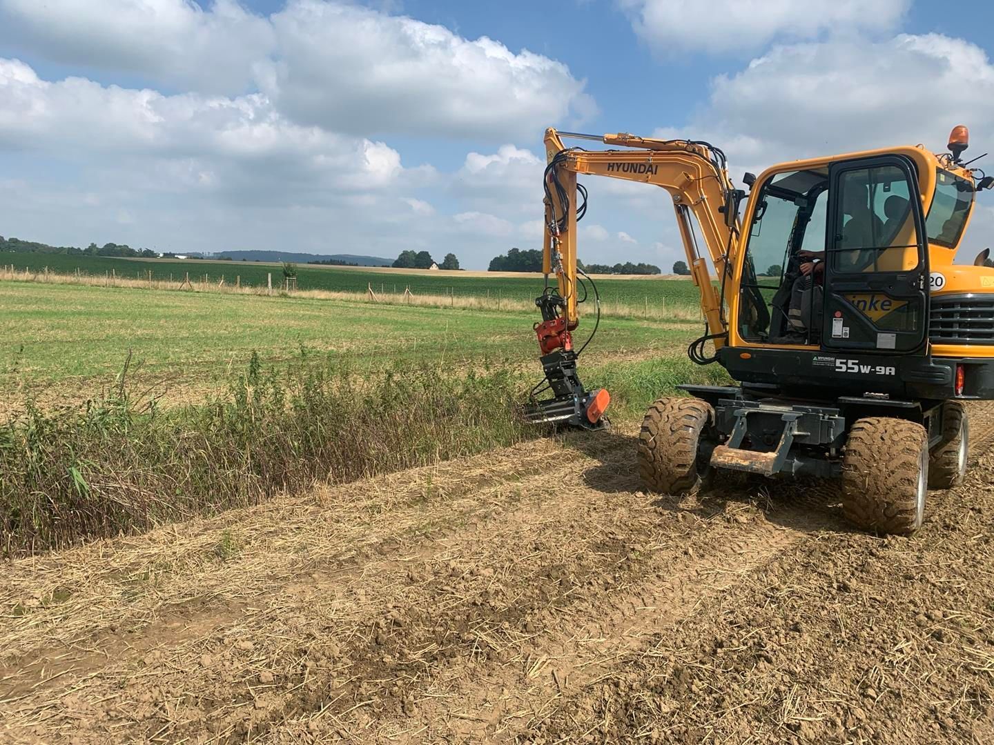 Ein gelber Bagger steht mitten auf einem Feld.