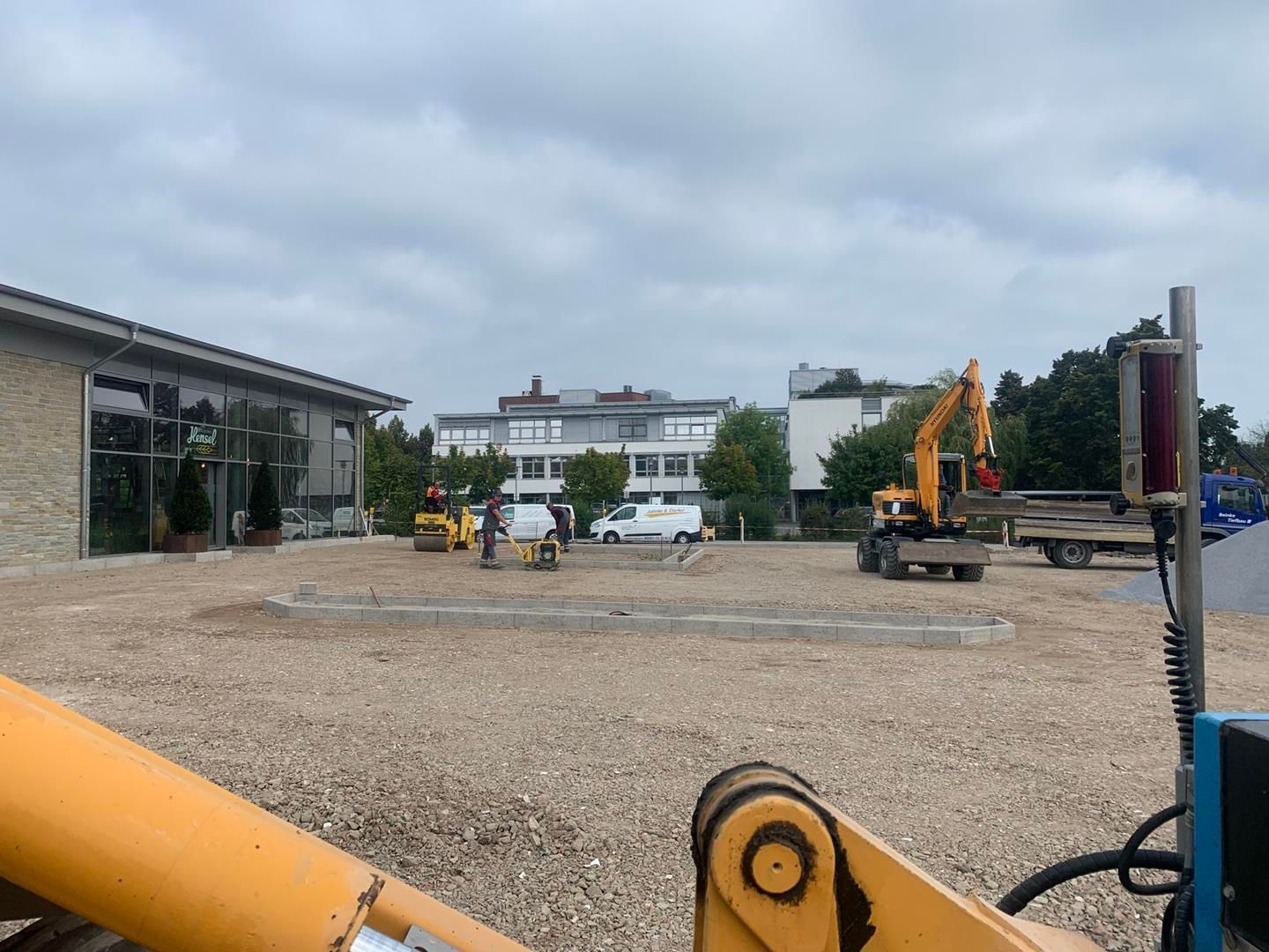 eine Baustelle mit einem Gebäude im Hintergrund und einem Traktor im Vordergrund.