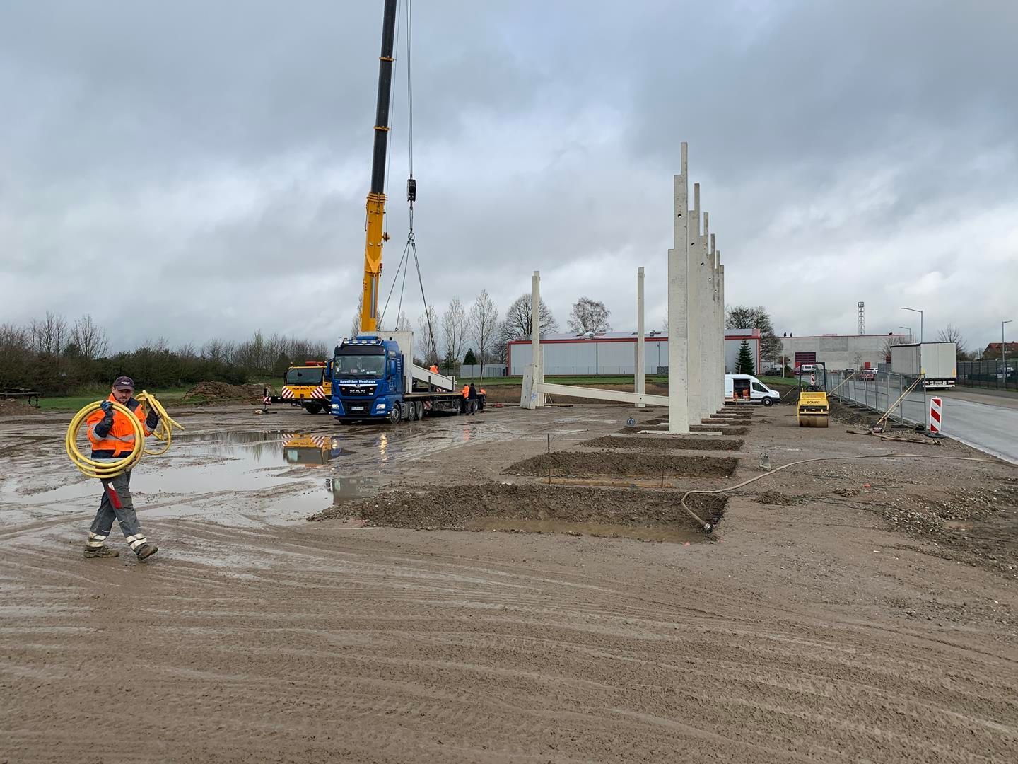 Eine Baustelle mit einem Kran und einem Mann, der einen gelben Schlauch hält.