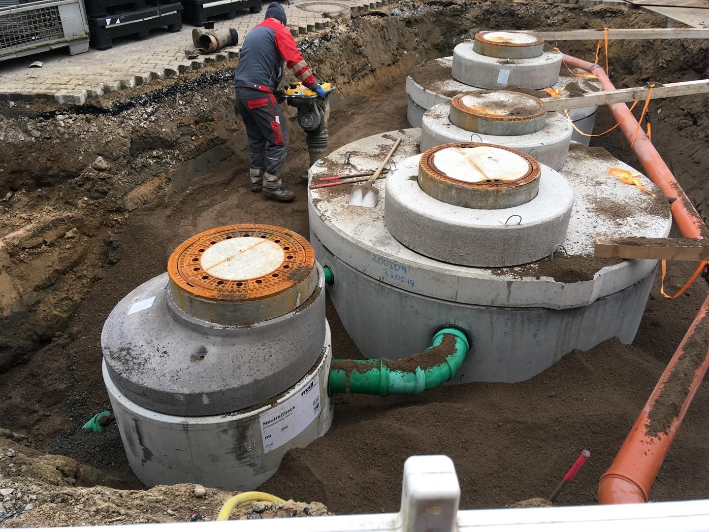 Ein Mann arbeitet an einer Klärgrube im Dreck.