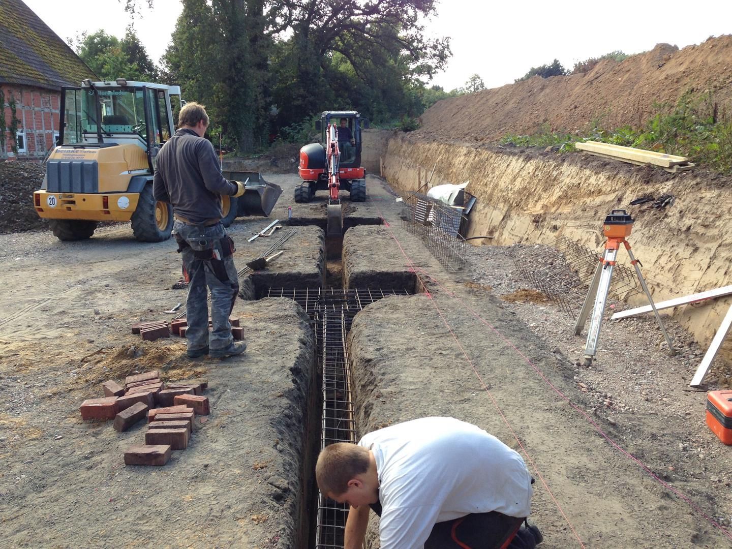 Ein Mann kniet im Dreck vor einem Traktor