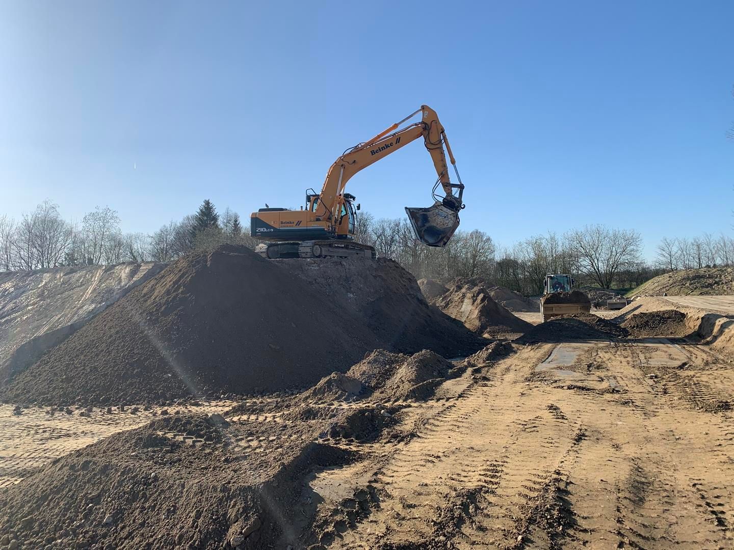 Ein großer Bagger arbeitet an einem Erdhaufen.