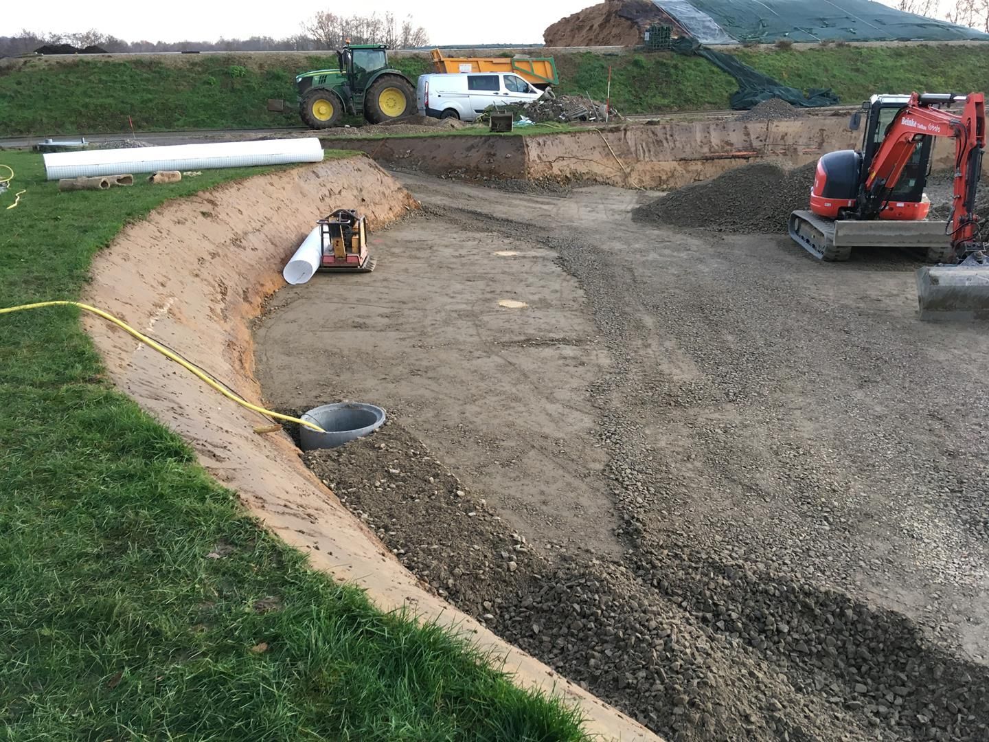 Ein Traktor fährt einen unbefestigten Weg entlang einer Wiese entlang.