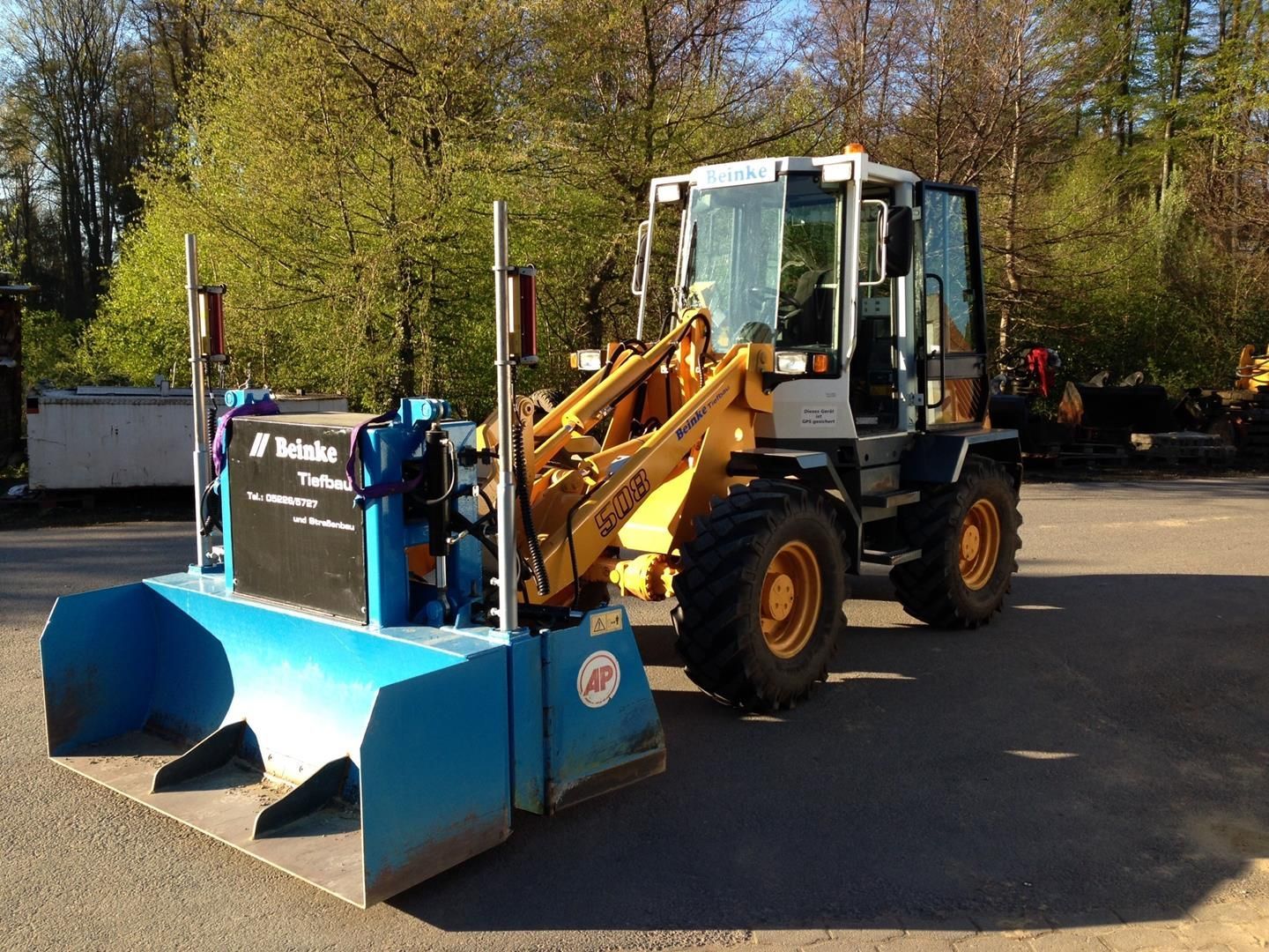 Ein gelb-weißer Traktor steht auf einem Parkplatz