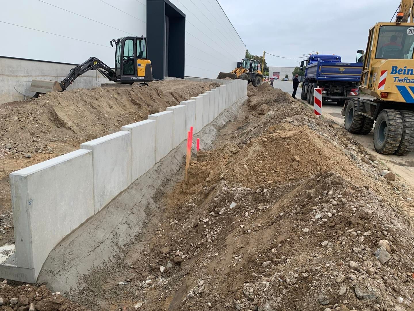 Vor einem Gebäude wird eine Betonmauer errichtet.