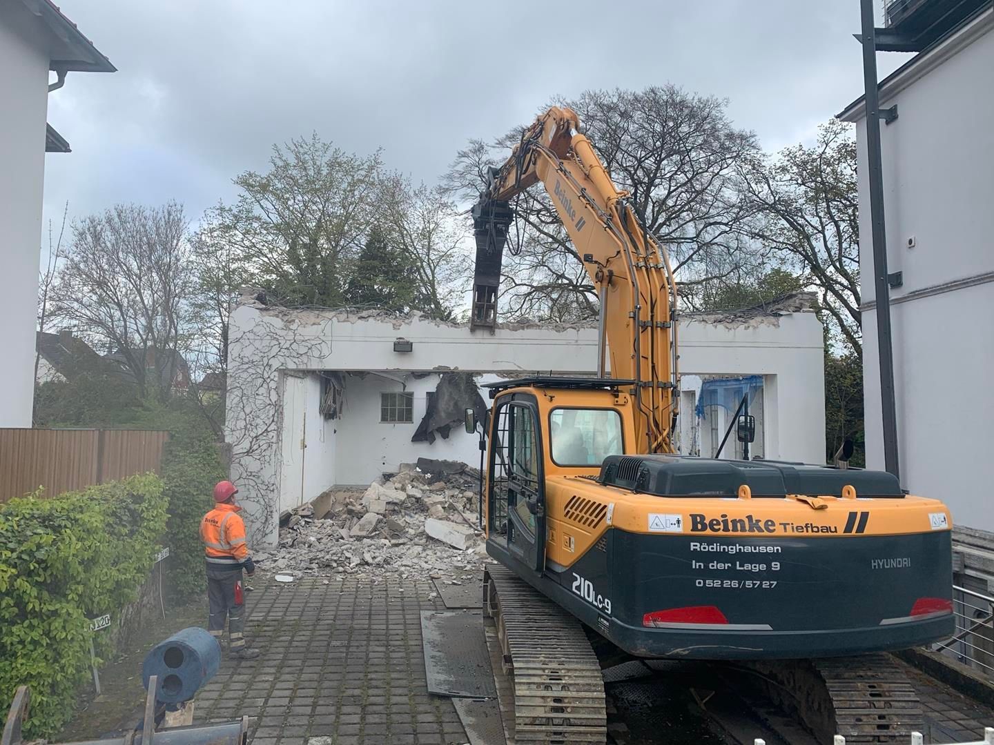Ein großer gelber Bagger zerstört ein Gebäude.