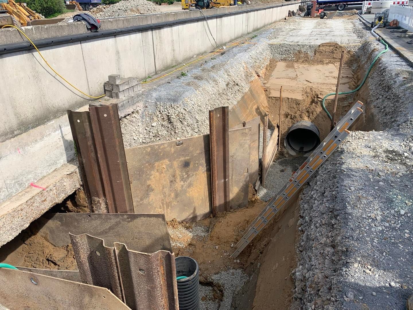 In einem Loch im Boden wird ein großes Rohr verlegt.