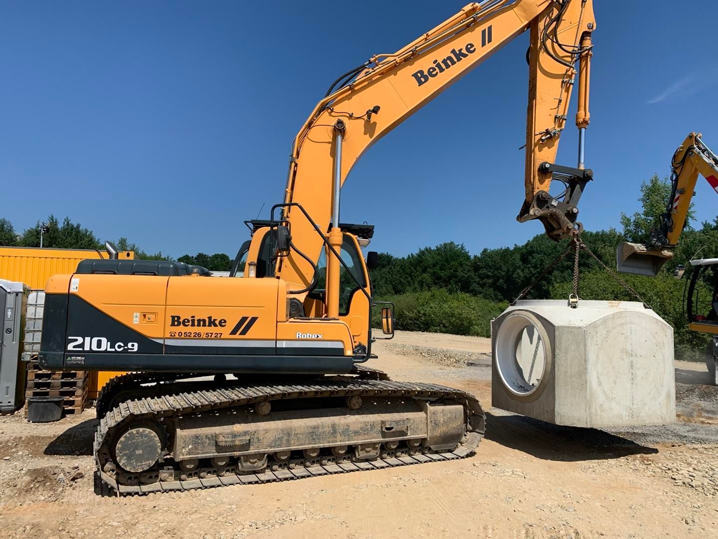 Ein gelber Bagger hebt einen großen Betonblock.