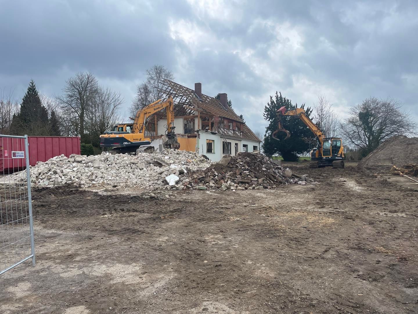 Auf einem großen Erdfeld wird ein Haus abgerissen.