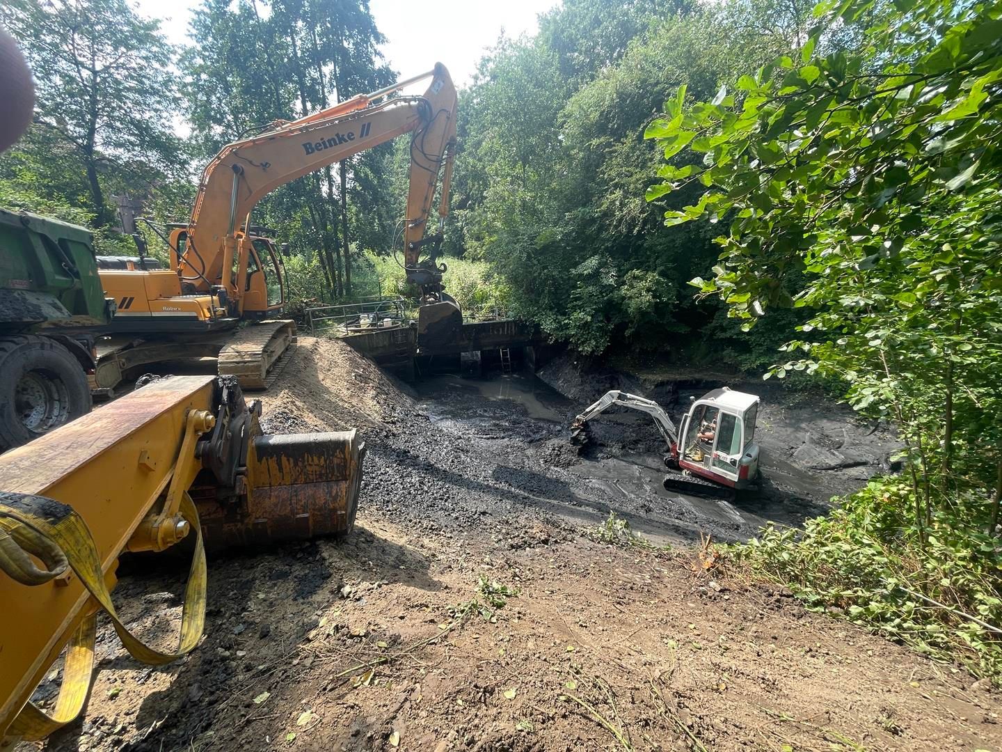 Ein paar Bagger arbeiten auf einer unbefestigten Straße.