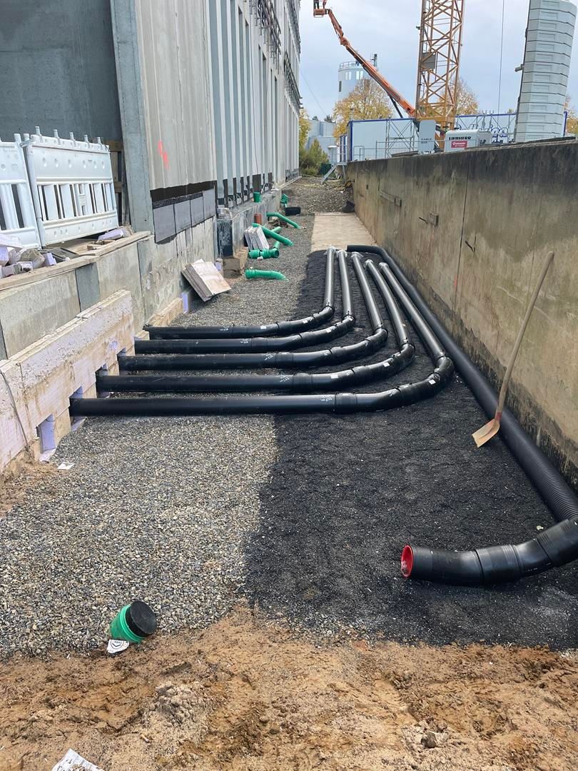 Ein Bündel Rohre liegt auf dem Boden vor einem Gebäude.