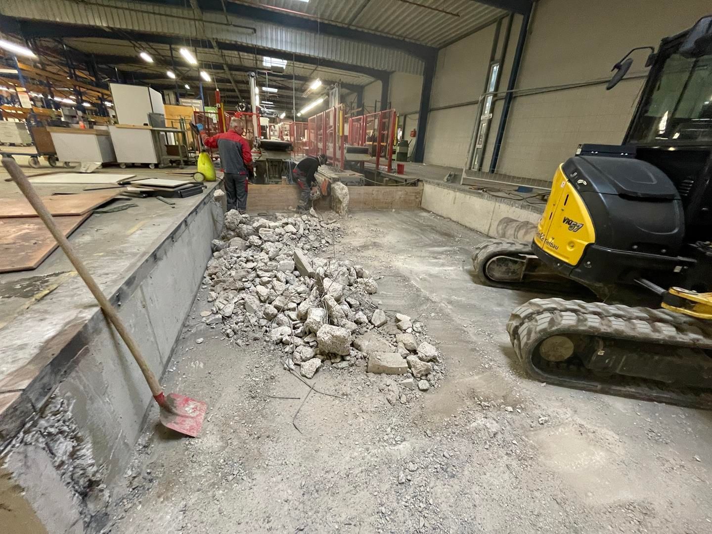 Ein Mann reinigt den Boden eines Gebäudes mit einer Schaufel.