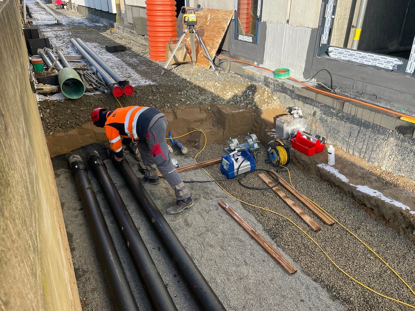 Ein Bauarbeiter gräbt ein Loch in den Boden, um Rohre zu verlegen.