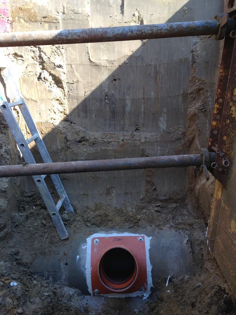 Eine Leiter steht neben einem Rohr im Dreck.