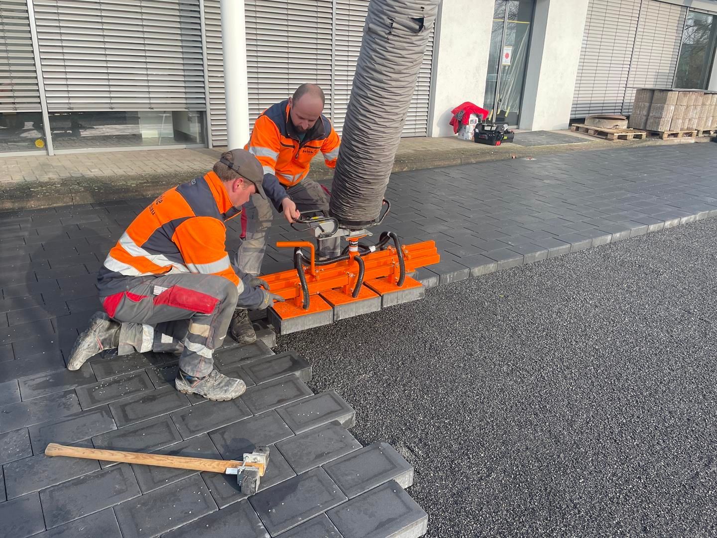 Zwei Männer arbeiten mit einer Maschine auf einem Bürgersteig.