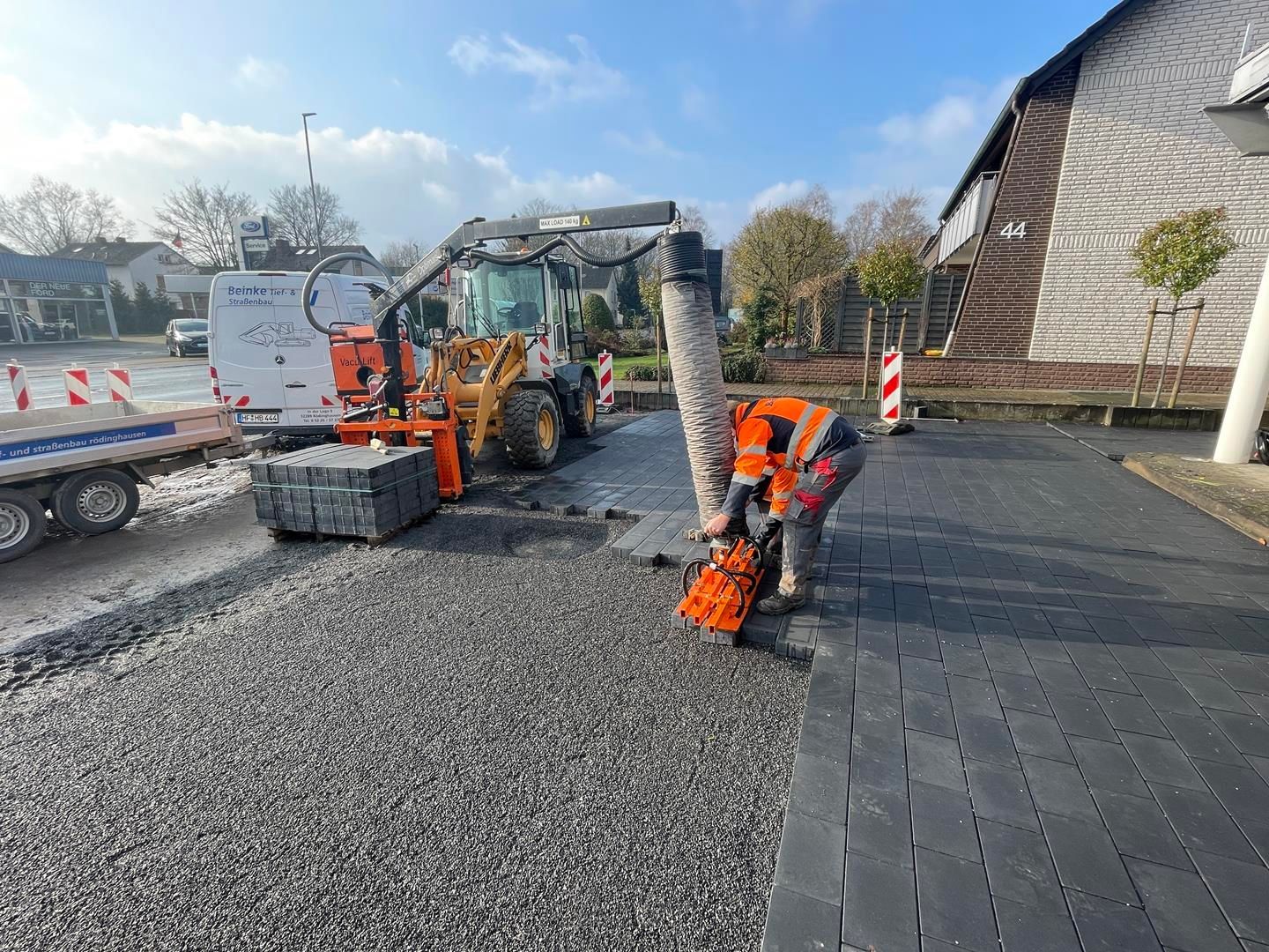 Ein Mann arbeitet an einer Einfahrt neben einem Traktor.