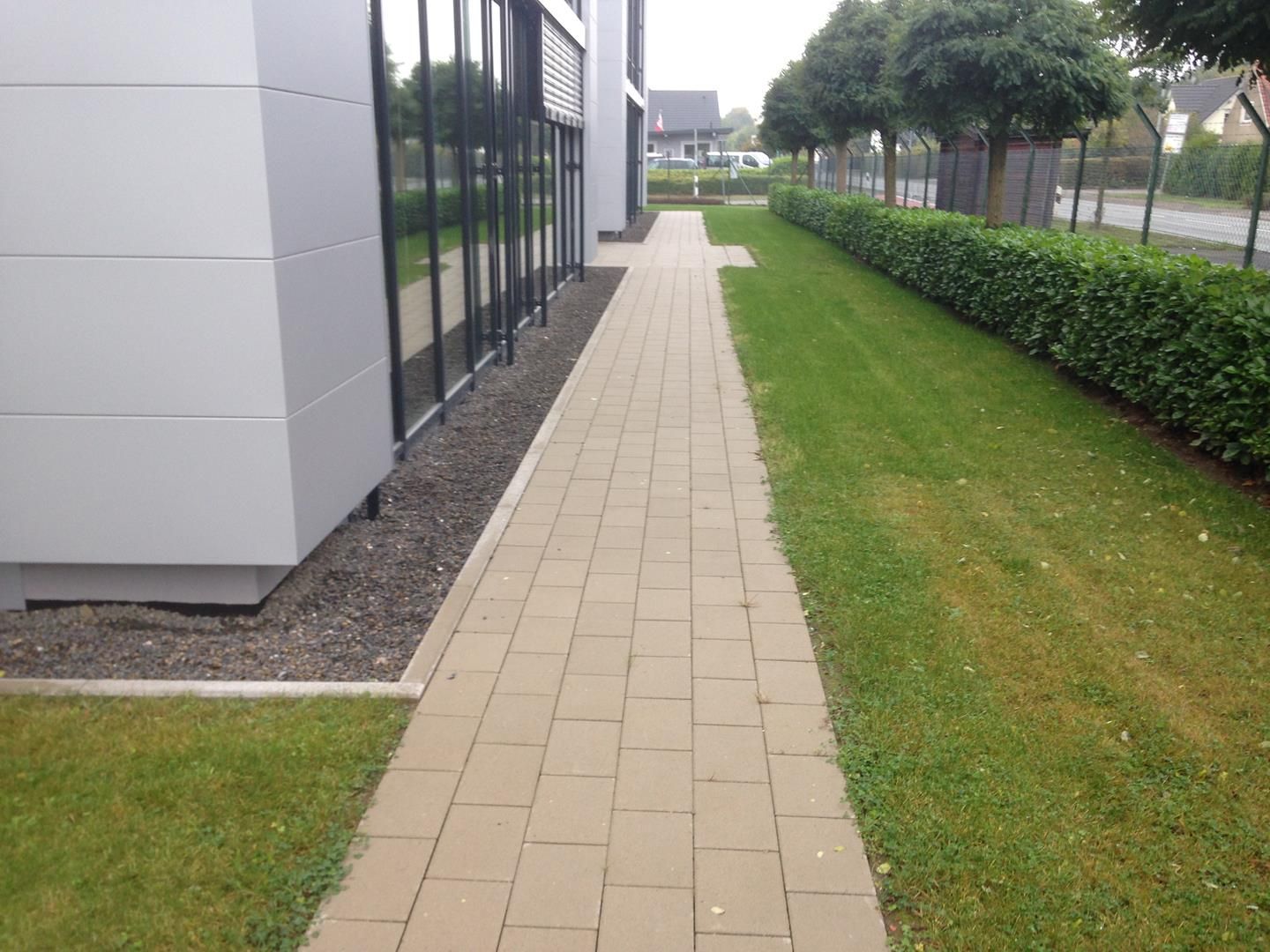 Ein gemauerter Gehweg, der zu einem Gebäude mit vielen Fenstern führt