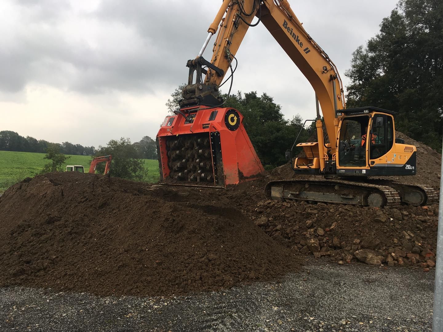 Ein großer gelber Bagger arbeitet an einem Erdhaufen.