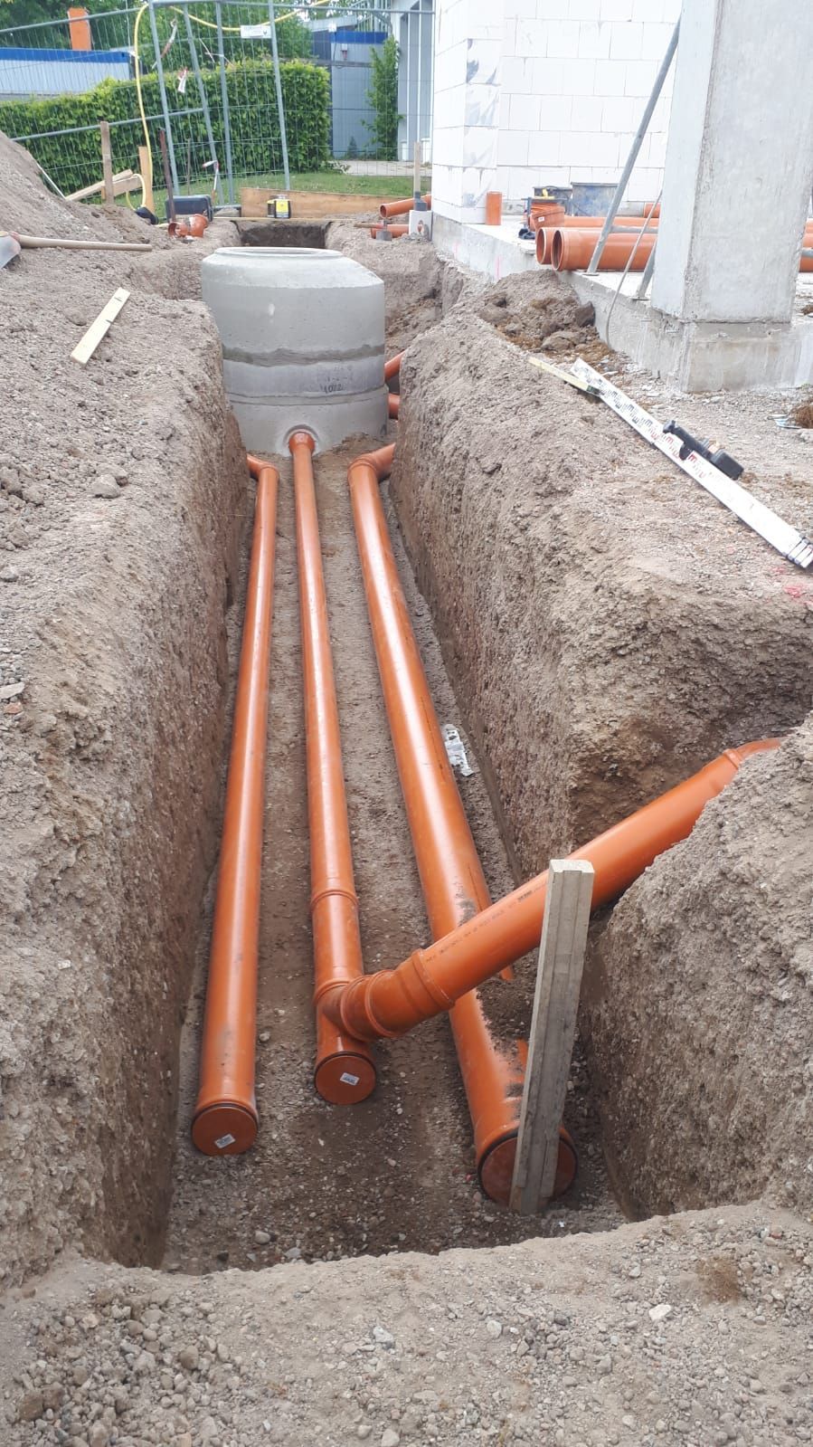 Ein Bündel orangefarbener Rohre liegt in einem Loch im Boden.