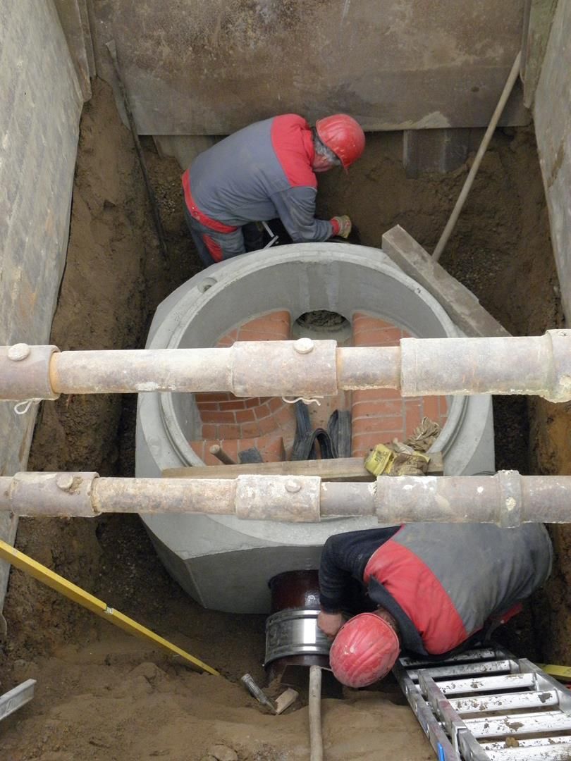 Eine Gruppe von Bauarbeitern arbeitet an einem großen Loch im Boden.