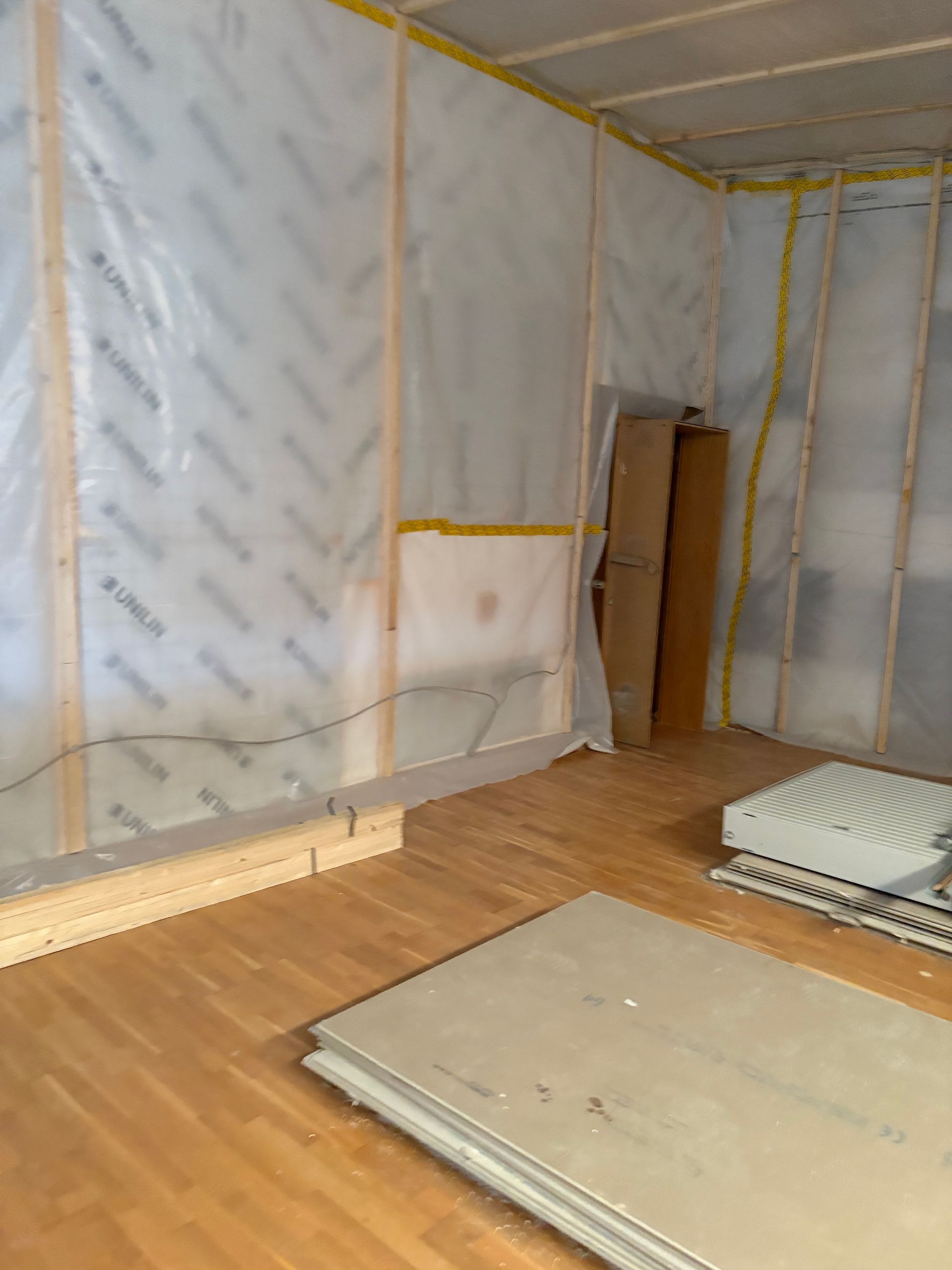 Innenansicht eines im Bau befindlichen Raumes mit vielen Fenstern und Gipskartonwänden und Decke.